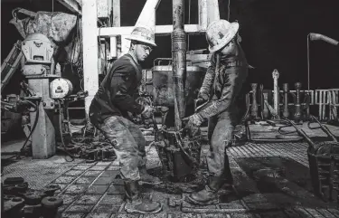  ?? Michael Ciaglo / Staff photograph­er ?? Helmerich &amp; Payne’s Michael Palmer, left, and Travis Palmer move equipment in 2016 as a section of pipe is drilled into the ground for oil and gas extraction on a Diamondbac­k Energy lease near Midland.