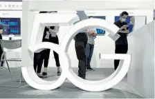  ?? Ng Han Guan, The Associated Press ?? Visitors walk past a 5G sign at the China Beijing Internatio­nal High Tech Expo in Beijing in September.