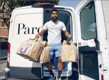  ??  ?? Andrew Chisholm grabs bags of food, ordered by Jet.com customers, for delivery in New York. Walmart, which has faced resistance in the city for years, has found a foothold through its e-commerce business Jet.