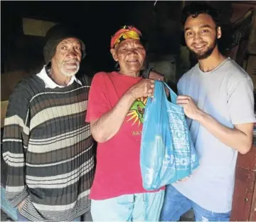  ?? Picture: DESMOND COETZEE ?? UBUNTU: Ziano Winlock delivers a food parcel to Bennie Kock, left, and his wife Katryn, on Bidhli Farm