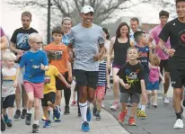  ?? JESSICA HILL/SPECIAL TO THE COURANT ?? Meb Keflezighi, center, Olympic silver medalist and winner of the Boston and New York City marathons, runs up Farmington Avenue with children and parents before an appearance at Fleet Feet in West Hartford.