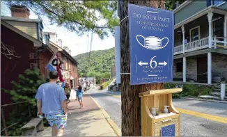  ?? COLLEEN MCGRATH/THE HERALD-MAIL ?? Hand sanitizer dispensers sit below a sign last week encouragin­g visitors to Harpers Ferry, W.Va., to wear masks and social distance to help stop the spread of COVID-19.