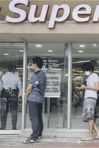  ??  ?? 0 As this queue outside a supermarke­t in Manila shows, social distancing is the