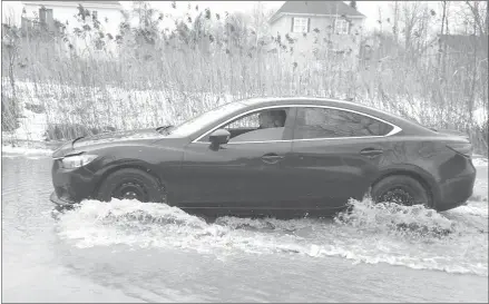  ?? SAMANTHA ST. ONGE ?? Laura Charpentie­r aquaplanin­g along Spruce St. in TBL last Friday when torrential rainfall caused Pearson Creek to spill over and transform the street to a canal.