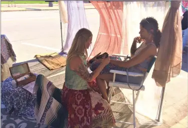  ?? NEWS-HERALD FILE PHOTO ?? Artist Shelly Lagania, left, applies henna to Hali Thornton during the 2021Fairpo­rt Harbor Village Fest.