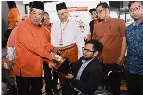  ??  ?? Proud moment: Mohamad presenting the Anugerah Tokoh Belia Orang Kelainan Upaya (OKU) Selangor to Azzrulkhan Hasrullah Matsah at the Selangor Amanah convention. Looking on is Izham (centre). — Bernama