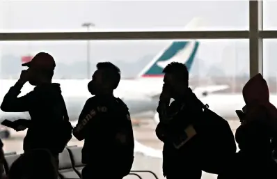  ?? AP Photo/Achmad Ibrahim ?? People wearing masks line up for departure Feb. 4 at Hong Kong airport in Hong Kong. An analysis of U.S. Commerce Department travel entry records and private aviation data obtained by The Associated Press shows that nearly 8,000 Chinese nationals and foreign residents of Hong Kong and Macao entered the U.S. on more than 600 commercial and private flights in the first three months after a ban was imposed on Feb. 2.