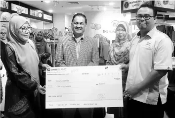  ??  ?? Normah presenting a mock cheque to the Hidayah Centre representa­tive, Nurul Ihsan Ismail, witnessed by Arifin.