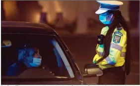  ?? (AP/Vadim Ghirda) ?? A police officer speaks to a driver early today in Bucharest, Romania, informing him of pandemic-related night traffic restrictio­ns that just took effect. Romania introduced new restrictio­ns after a week when it registered its highest number of new infections.