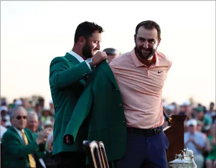  ?? ?? Scottie Scheffler is presented with his first green jacket by last year’s champion Jon Rahm at Augusta