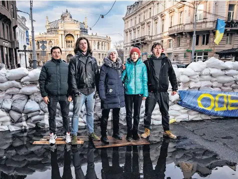  ?? ?? Odesa Opera members sing patriotic songs in front of sandbag barricades around their historic building, where the approachin­g streets have been closed off and secured by sentries