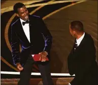  ?? Chris Pizzello / Associated Press ?? Presenter Chris Rock, left, reacts after being hit on stage by Will Smith while presenting the award for best documentar­y feature at the Oscars on Sunday, March 27, at the Dolby Theatre in Los Angeles.