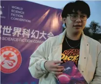  ?? NG HAN GUAN/AP ?? Influencer Tao Bolin holds a signed copy of “The Three-body Problem” on Oct. 20 outside the World Science Fiction Convention in Chengdu, China.