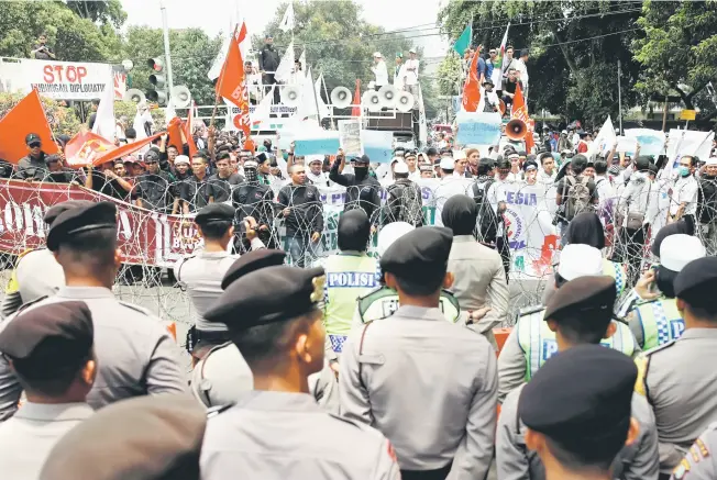  ?? — Gambar Reuters ?? MELONTARKA­N KETEGASAN: Penunjuk perasaan mengadakan rapat umum memprotes Myanmar di luar kedutaan Myanmar di Jakarta, semalam.