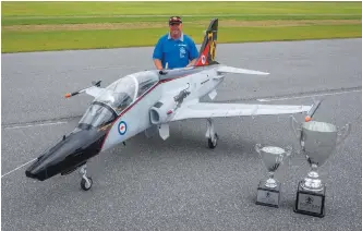  ??  ?? A winner with his award-winning aircraft, Peter shows off his BAE Hawk and some of the hardware he earned at the Top Gun Scale Invitation­al.