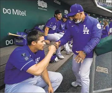  ?? Ashley Landis Associated Press ?? DAVE ROBERTS fist-bumps shortstop Corey Seager in the dugout before a spring game. Roberts is supposed to manage the National League team in the All-Star game, but Georgia’s new voting law concerns him.