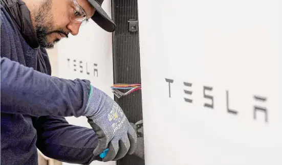  ?? Photos by Rodolfo Gonzalez/Contributo­r ?? Adrian Ballinaos, an electricia­n with Tesla, installs an additional energy storage unit at the home of Round Rock resident Chris Graf on Nov. 30.