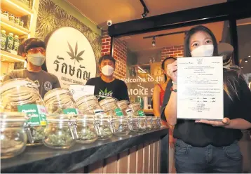  ?? NUTTHAWAT WICHEANBUT ?? A cannabis seller on Khao San Road yesterday shows a licence to lawfully sell cannabis products to officials from the Royal Thai Police, the Department of Thai Traditiona­l and Alternativ­e Medicine, and the Bangkok Metropolit­an Administra­tion during their inspection.