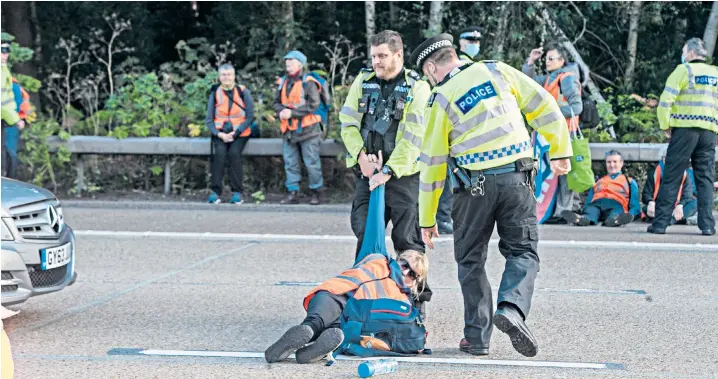  ?? ?? Suffragett­e city: Officers drag a woman off the motorway near Cobham in Surrey yesterday