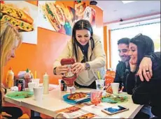  ??  ?? SABA MASH, visiting L.A. with friends Hani Kashef, left, and Shahin and Mojdeh Croes, squirts ketchup on a pizza at Cafe Glace.