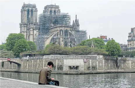  ?? /Omar Havana/Getty Images) ?? Outer walls: A man draws the damage caused to Notre-Dame Cathedral on April 16 in Paris, France. A fire broke out on Monday afternoon and quickly spread across the building, causing the famous spire to collapse. The cause is unknown but officials have said it was possibly linked to ongoing renovation work.