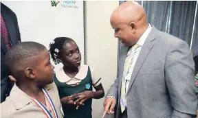  ?? JERMAINE BARNABY/FREELANCE PHOTOGRAPH­ER ?? Mark Chisholm (right), executive vice-president, Individual Life Insurance Division, Sagicor, having words with Tajay Shaw (left) of New Day Primary and Junior High and Ramoya Thompson of Old Pera Primary and Infant School, at Thursday’s launch of the...