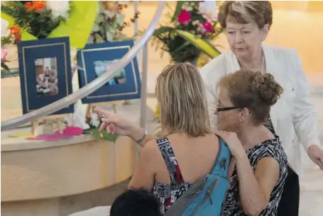  ?? JUSTIN TANG/POSTMEDIA NEWS ?? Residents pay their respects inside Sainte-Agnes Church in Lac-Mégantic on Sunday, as tourists saw what they could from the church steps outside.