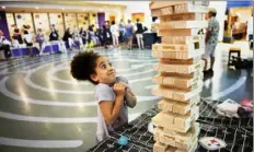  ?? Steve Mellon/Post-Gazette ?? Lailah Trimbur, 6, plays Jenga in the atrium at UPMC Children’s Hospital of Pittsburgh in Lawrencevi­lle in August 2018. Her brother at the time was a patient at the hospital. The game is a finalist for the National Toy Hall of Fame.