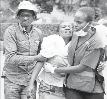  ?? ASSOCIATED PRESS ?? Kenya Red Cross staff help a woman after she viewed the body of a relative killed in Thursday’s attack at Garissa University College in Garissa. Bodies of the 148 killed were at a morgue in Nairobi for family members to identify and claim.