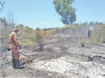  ??  ?? Firefighte­rs put out the bushfire near Marina Square.