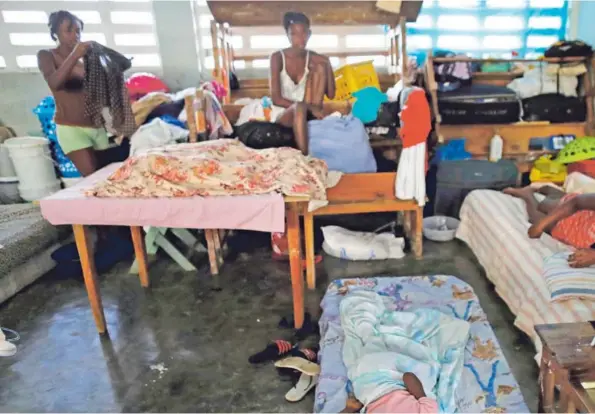  ?? AP Y AFP ?? Personas que perdieron su vivienda se encontraba­n en un albergue en una escuela de la localidad de Port Salut. Mientras, una mujer yacía sobre el lugar donde estuvo su casa en Les Cayes.