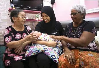  ?? — Bernama photo ?? Despite their different religion and racial background­s, it is not a hindrance for these two women, Lee (left) and Puspam (right) to take care of Izzati who is still in confinemen­t after giving birth.