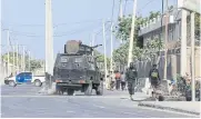  ?? ?? TERROR ALERT: Security forces patrol outside a building which was attacked by suspected Al Shabaab militants in Mogadishu on Feb 21.