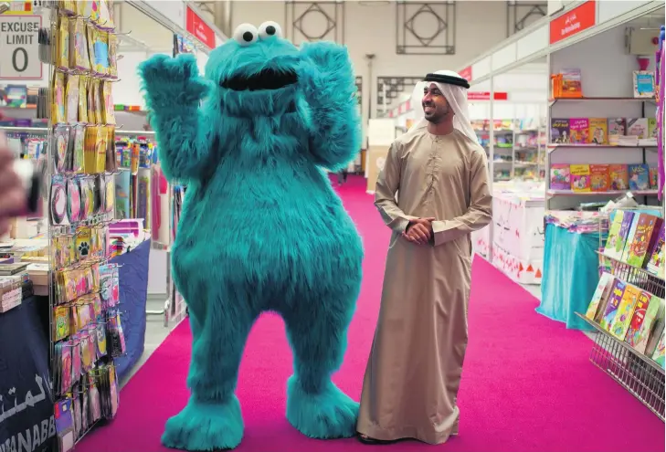  ?? Razan Alzayani / The National ?? The creative director of the new version of Iftah Ya Sim Sim, Abdalla Al Sharhan, with the Sesame Street muppet Cookie Monster, known as Kaaki in the Arab version, at the Al Ain Reads Bookshow.