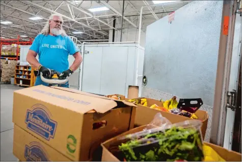  ?? DANIEL PASSAPERA/SPECIAL TO THE DAY ?? Employee Jon Straut wheels produce into a fridge May 26 at the Gemma E. Moran United Way/Labor Food Center in New London. Donations for nonprofits like the United Way have been declining due to recent inflation and supply chain shortages.