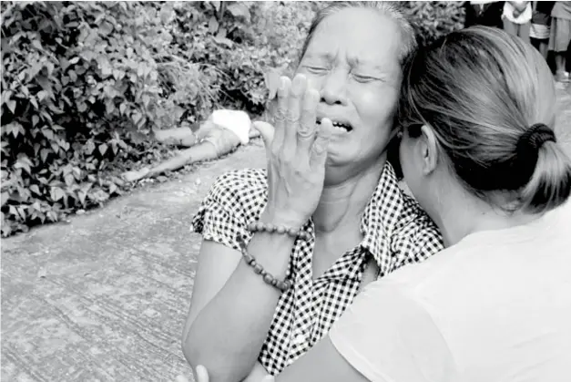  ??  ?? CEBU. Remy Lugan (left) cries as she identifies the body that was found in a subdivisio­n in Talisay City as that of her daughter, May Albasin, a lotto outlet caretaker. (SunStar Cebu/Allan Tangcawan)