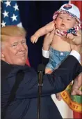  ??  ?? Final BlitZ: Donald Trump holds a baby at a rally yesterday
