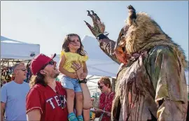  ?? TOM MCCARTHY JR. FOR AMERICAN-STATESMAN ?? Sitting on her uncle Jose Oviedo’s shoulder, Ive Garcia, 2, debates giving a high-five to a creepily costumed Rue Neumann from Scream Hollow Wicked Halloween Park during Bat Fest 2017.