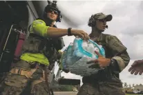  ?? CHRISTOPHE­R LEE/THE NEW YORK TIMES ?? Senior Airman Adam Secore, a pararescue team member, hands off bottled water Thursday at a military staging area in Beaumont, Texas. For the second day in a row, Beaumont was without running water Friday.