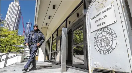  ?? JOHN SPINK/AJC 2020 ?? A security guard at the Georgia Department of Labor in Atlanta walks past the unemployme­nt certificat­ion drop box in front of the office. Unemployme­nt claims have skyrockete­d since the COVID-19 pandemic shut down businesses across the state and nation.