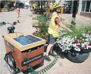  ?? BRANDON HARDER ?? Jen Rumancik uses the city’s new solar-assisted watering tricycle on Scarth Street. The $5,000 trike ordered from Holland can water up to 20 flowers pots.