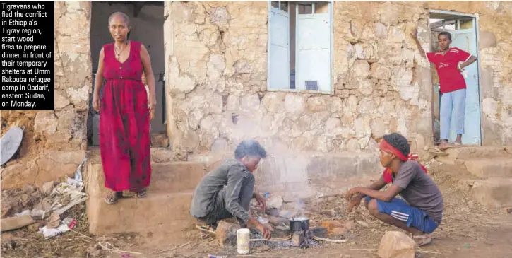  ??  ?? Tigrayans who fled the conflict in Ethiopia’s Tigray region, start wood fires to prepare dinner, in front of their temporary shelters at Umm Rakouba refugee camp in Qadarif, eastern Sudan, on Monday.