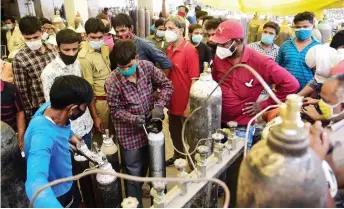  ??  ?? People refill medical oxygen cylinders for Covid-19 coronaviru­s patients at an oxigen refile station in Allahabad.