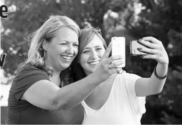  ?? — Mark A. Philbrick/BYU photo ?? Syd and Jacques take photos of themselves on their smart phones. Coyne research that Teens feel closer to parents when they connect on social media.