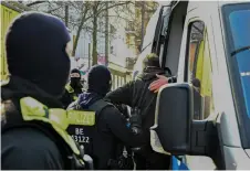  ?? — AFP photo ?? Police officers assist a detained man in climbing into a police car in Berlin after police arrested two men during a manhunt for two members of the far-left militant Baader-Meinhof gang.