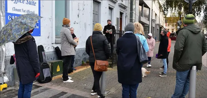  ??  ?? First Stop……Marcel Krueger reads to the audience on the steps of the Old Queen’s Hotel as part of the Pop Culture Walking Tour of Dundalk. Picture Ken