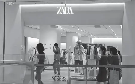  ?? WANG GANG / FOR CHINA DAILY ?? Customers walk past a Zara store in Shanghai in May.