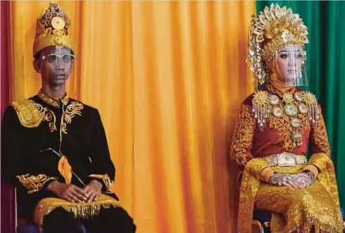  ??  ?? PELAJAR berpakaian tradisiona­l serta mengenakan perisai muka untuk pencegahan Covid-19 menghadiri majlis graduasi sebuah sekolah farmasi di Banda Aceh, Indonesia, semalam. - AFP