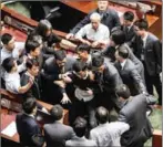  ?? ANTHONY WALLACE ?? Newly elected lawmaker Baggio Leung (centre) is restrained by security after attempting to read out his oath at Legco in Hong Kong yesterday.