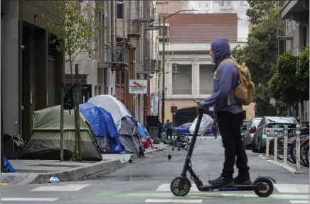  ?? PHOTOS BY KARL MONDON — STAFF PHOTOGRAPH­ER ?? A commuter on a scooter cruises up Polk Street past a homeless camp in an alley near San Francisco's Civic Center on May 25. Such blighted sights and a rise in crime rates across the board are forcing some city residents to question how liberal they can remain if conditions worsen.